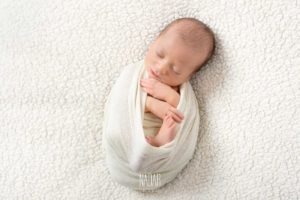 neonato avvolto in un tessuto durante un servizio fotografico