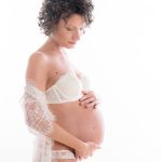 Donna in intimo durante servizio fotografico di gravidanza