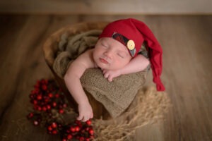 neonato che dorme nel mastello , con cappellino rosso